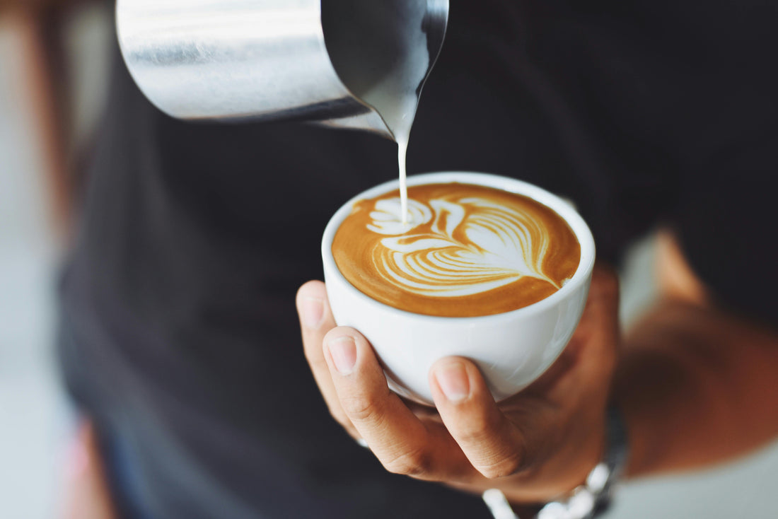 A barista pouring a latte with latte art