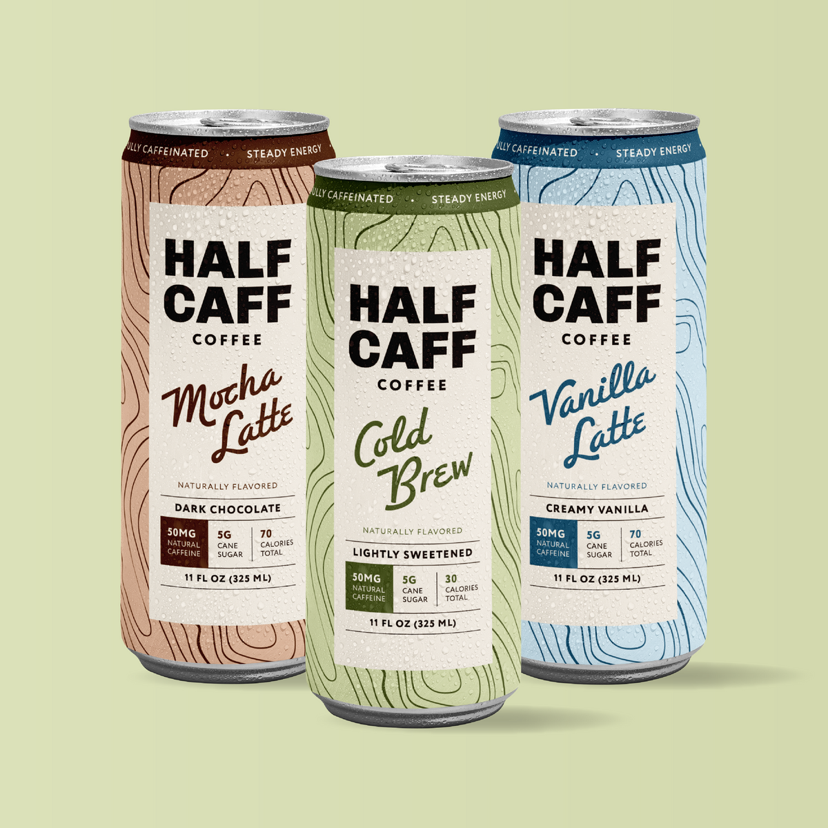 Three Half Caffe Coffee cans shown on a pale green background: Mocha Latte in a brown wood-grain design, Cold Brew in a green wood-grain design, and Vanilla Latte in a light blue wood-grain design.
